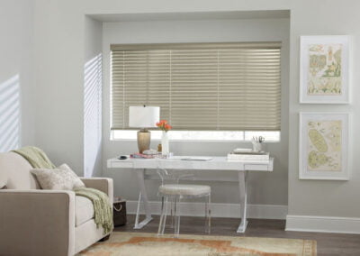 metal-colored horizontal window coverings with desk and comfy chair